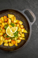 top view tasty fried potatoes inside pan with lemon slices on a dark background cuisine photo color food meal