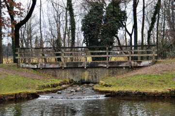 Fototapeta na wymiar Pond and stone bridge. Bridge over a small stream. Panorama of the park.