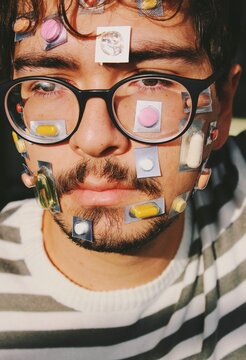 person with glasses face covered with pills and medication , abstract image for flu / covid treatment 
