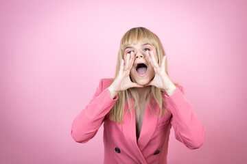 Young caucasian woman over isolated pink background shouting and screaming loud to side with hands...