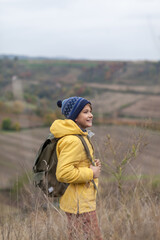 Happy little hiker walking through tall grass in autumn day on a hill.