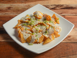 Cheese Nachos - A classic Mexican appetizer made from corn tortilla chips. topped with cheese. served over a rustic wooden background, selective focus