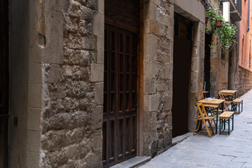 Naklejka na ściany i meble Cafe with terrace on a narrow street with medieval historic houses in Barcelona