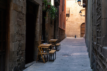 Fototapeta na wymiar Cafe with terrace on a narrow street with medieval historic houses in Barcelona