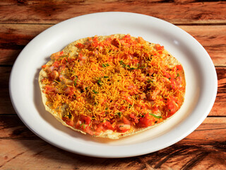 Masala Papad is a delicious Indian snack made using roasted or fried papad topped with a tangy and spicy onion tomato mix, served over a rustic wooden background, selective focus