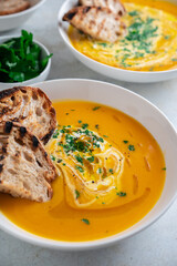 Pumpkin soup served in a bowl with croutons, parsley and olive oil.
