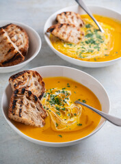 Pumpkin soup served in a bowl with croutons, parsley and olive oil.