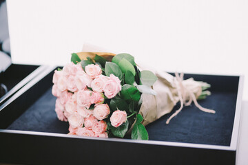 Wedding. The girl in a white dress and a guy in a suit sitting on a wooden chair, and are holding a beautiful bouquet of white, blue, pink flowers and greenery, decorated with silk ribbon