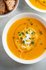 Pumpkin soup served in a bowl with croutons, parsley and olive oil.