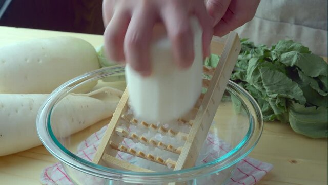 Grating daikon radish with traditional japanese bamboo grater