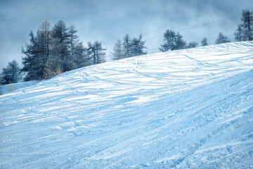 Mountain ski slope background on the skiing resort. Active winter holiday. European ski resort in alpine mountains. Ski and snowboard free ride tracks in powder snow