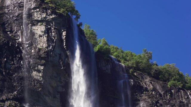 The Sven sisters waterfall - an iconic feature of the Geiranger fjord, Norway. Seven steams, some full and turbulent, some wispy and thin,  falling from 250-meter cliffs. Trees cling to the rocks.