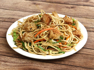 Chicken Noodles a popular indo chinese dish made with chicken, noodles and vegetables, served over a rustic wooden background, selective focus
