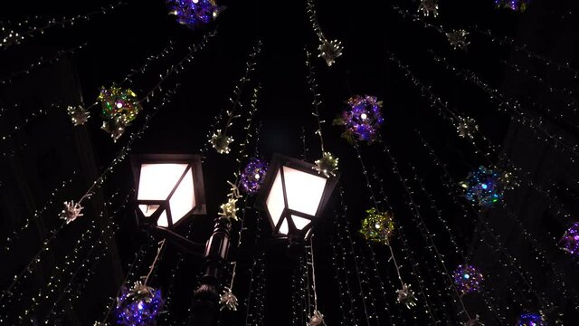 Lamppost around hanging luminous bulbs on the street at night