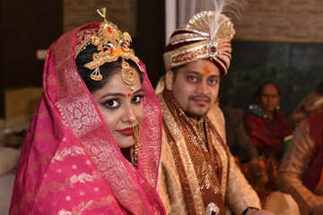 Indian wedding couple posing for photograph. Beautiful bridal makeup of bride is visible with groom in bokeh effect
