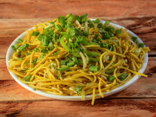 Veg Hakka Noodles a popular oriental dish made with noodles and vegetables, served over a rustic wooden background, selective focus
