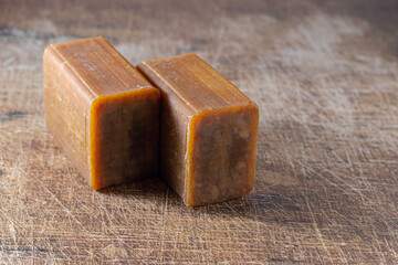 two pieces of brown natural soap on a wooden surface