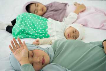 Muslim new born baby girl wearing HIJAB with sister kissing sleeping on white bed at home. 