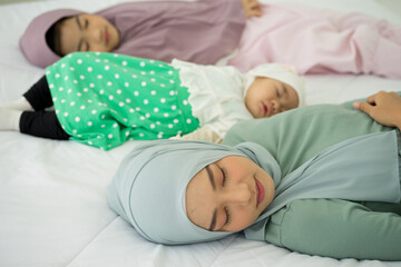 Muslim new born baby girl wearing HIJAB with sister kissing sleeping on white bed at home. 