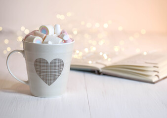 Marshmallow and in a cup with a pattern and a book on the table.
