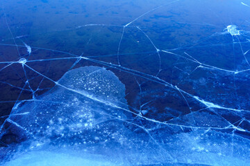 Fresh transparent ice on the Moscow river with cracks. The bottom of the river is visible through the ice