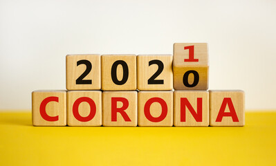 Concept of covid-19 pandemic in 2021. Fliped a wooden cube and changed the words 'corona 2020' to 'corona 2021'. Beautiful yellow table, white background, copy space.