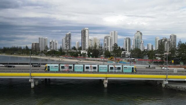 Moving Aerial view of a busy mains road bridge spanning across a popular waterway with a city skyline in the background