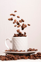 flying roasted coffee beans on a classic white mug in front of a white background isolated