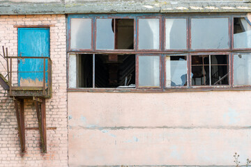 an abandoned factory. The destroyed building of the enterprise. Poverty and poor standard of living. Industrial collapse. Broken Windows and roof.