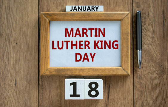 MLK Day symbol. Picture frame with words 'Martin Luther King Day' on beautiful wooden table, metalic pen and wooden calender with date January 18. MLK Day concept.