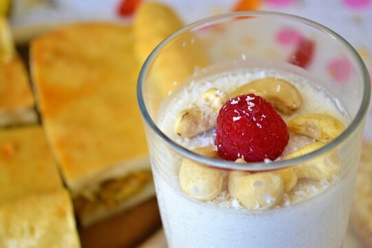 Closeup Of A Coconut Jelly Dessert With Cashews And A Raspberry On A Table With Pieces Of Empanada Behind