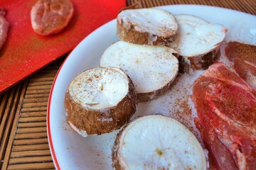 Plate with spiced lamb chops and cassava slices on a wooden table