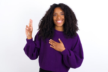 Young beautiful African American woman wearing knitted sweater against white wall smiling swearing...