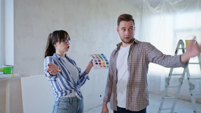 wife and husband quarrel at home during repairs, girl is nervous and waves a sheet of paper with colors in front of a man