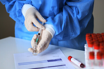 Doctor preparing the coronavirus COVID-19 vaccine. Hand with protective rubber gloves holding syringe and medicine vial for Coronavirus vaccine injection.