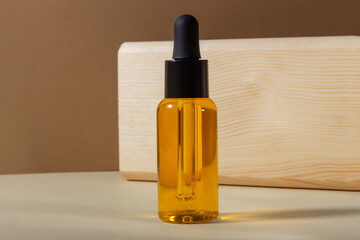 Naklejka premium A glass cosmetic bottle with a dropper on a beige background in bright sunlight. The concept of natural cosmetics, natural essential oil.