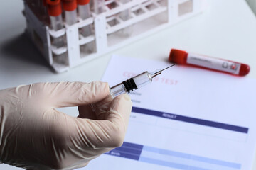 Vaccine in a bottle with a syringe, Glass bottle with a transparent antibiotic or vaccine in the hands in  latex gloves. Covid-19