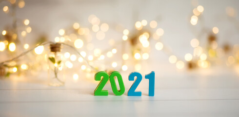 Figures 2021 on a background of garlands and bokeh. Blue, green, gold, white,  yellow background. New year banner