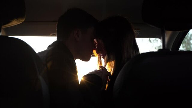 Portrait of young  pretty lovers looking at each other with tenderness and sitting in car at sunset. Moment before a romantic kiss. Concept of love