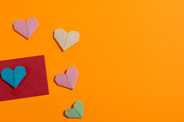 Origami hearts made with colored paper for congratulations on Valentine's Day for couples in love, on yellow background