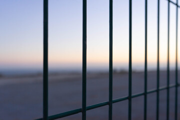 sunset in the city coast through a fence