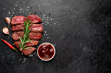 Different degrees of roasting beef steak in heart shape with spices on a stone background with a copy of the space for your text.