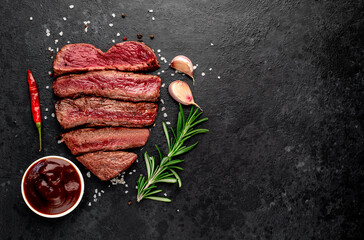 Different degrees of roasting beef steak in heart shape with spices on a stone background with a...