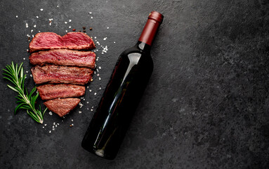 Different degrees of roasting heart-shaped beef steak with spices and bottle of wine on a stone background. valentines day celebration concept