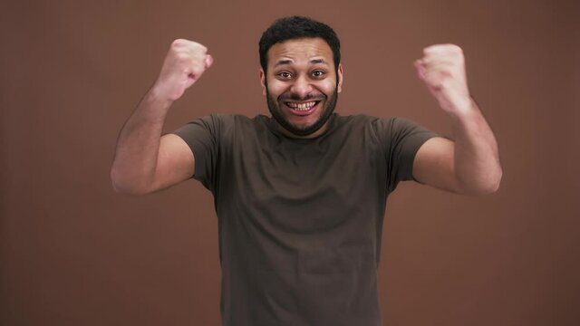 Success. Emotional indian man celebrating achievement, looking around and screaming, shaking fists in enjoyment
