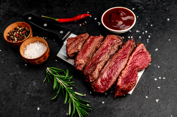 Different degrees of roasting heart shaped beef steak with spices on a meat knife on a stone background with copy space for your text