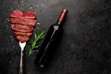 Different degrees of roasting heart-shaped beef steak with spices on a meat fork and a bottle of...