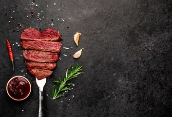 Fotobehang Different degrees of roasting beef steak in heart shape with spices on a meat fork on a stone background with a copy of the space for your text © александр таланцев