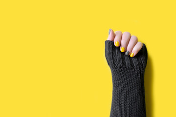 Detail of womans hand wearing gray sweater with manicure