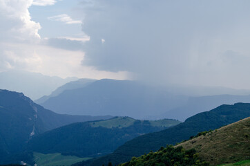 Beautiful view of the peaks of Monte Baldo. Stunning cloudy and panoramic view. Green Pastures in Italian Alps
